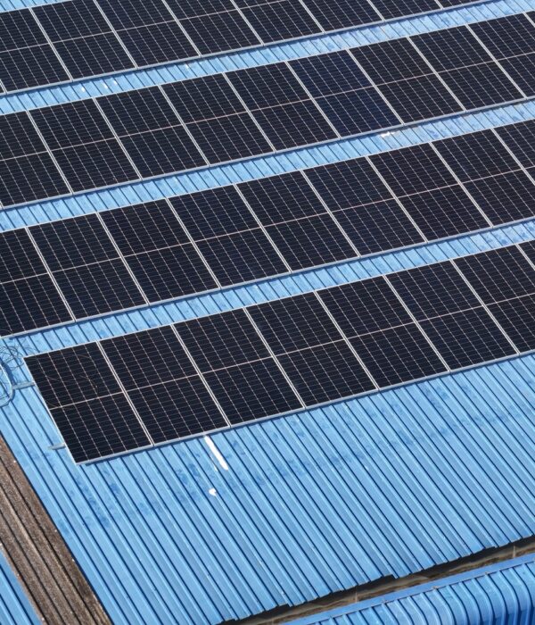Solar panels installed on a roof of a large industrial building or a warehouse. Industrial buildings in the background. Horizontal photo. default